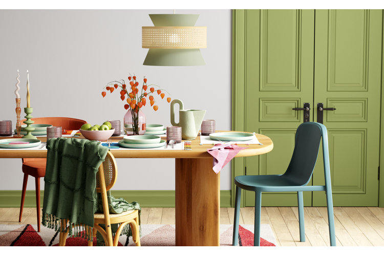 Dining room with green painted double doors and a green chandelier over a dining table with pastel green plates.