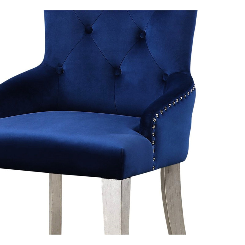 Fauteuil de salle à manger moderne en tissu bleu luxueux avec dossier capitonné et pieds fuselés en bois. Siège rembourré et tablier.