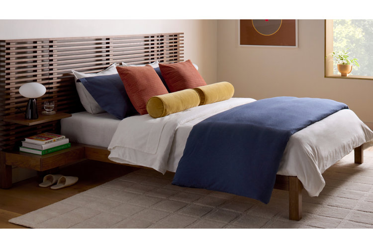 mid-century modern bedroom with a wood bed, primary-color bedding, and a cream area rug