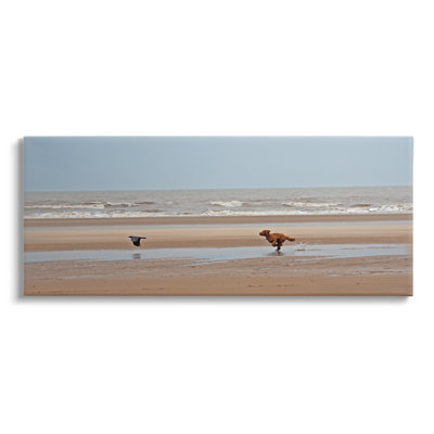 «Dog Chassing Bird on Beach» par Gill Woodcock - reproduction d'art sur toile tendue