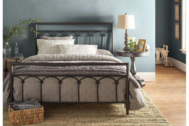 traditional bedroom with gray quilted bedding on a black iron bed frame