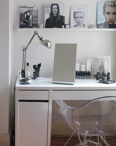 A monochrome bedroom with pixar lamp and clear plastic bucket chair