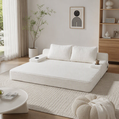 Canapé-lit 2 en 1 en velours côtelé beige de 180 cm de large, avec deux coussins décoratifs, porte-gobelets intégrés aux accoudoirs et poches de rangement latérales ; idéal pour les salons, les chambres et les espaces de détente.