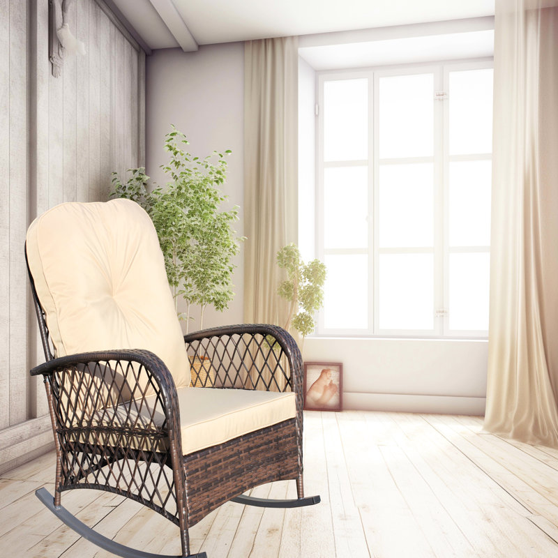 Fauteuil à bascule d'extérieur, modèle spacieux avec accoudoirs, structure robuste en acier, idéal pour terrasse, jardin ou cour arrière. Chaise basse brune avec coussin, protégée et adaptée à une utilisation extérieure.