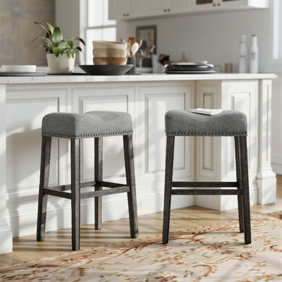 Tabourets de bar sans dossier Oenone, siège de selle rembourré avec garniture cloutée, pieds en bois patiné - ensemble de 2