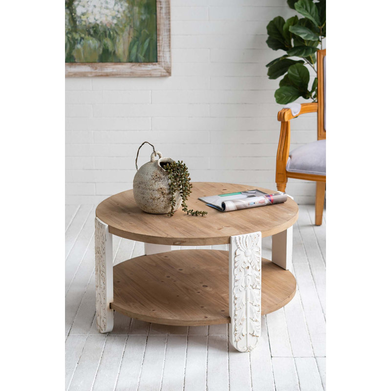 Table basse ronde en bois avec finition brun naturel, pieds sculptés blancs et tablette de rangement inférieure