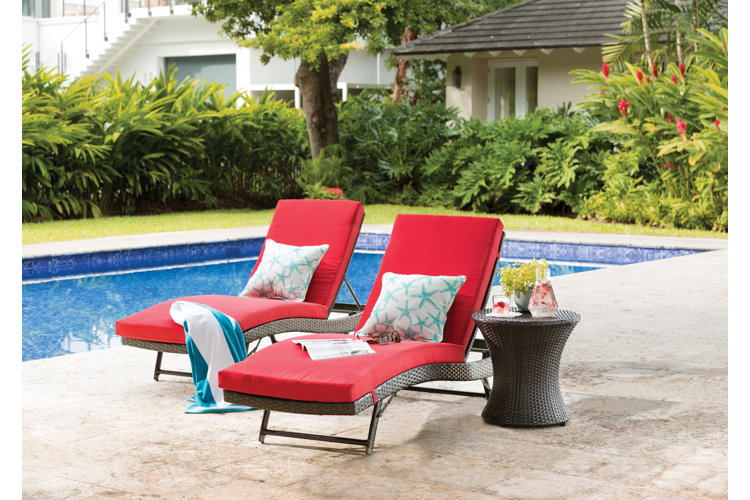 two lounger chairs with red cushions and a small side table