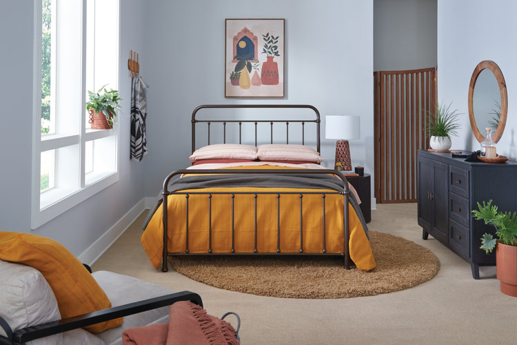 boho bedroom with blue walls, a full-sized metal bed with yellow bedding, and a brown shag area rug