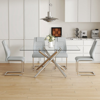Ensemble de table de salle à manger moderne et luxueux en verre trempé transparent avec chaises gris foncé et pieds en métal argenté, pour des expériences culinaires élégantes.