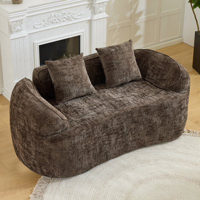 Brown Curved two - person compress  sofa. It has armrests on both sides, comes with two pillows, is  for small - sized apartments