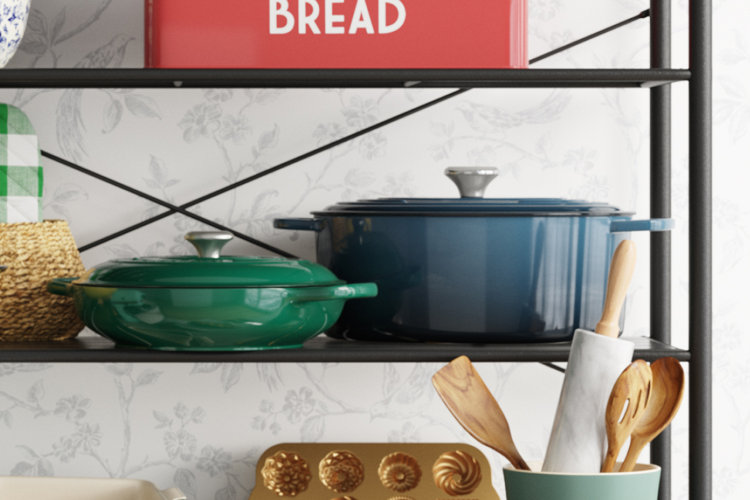 Green dutch oven and braiser on a wooden kitchen cabinet.