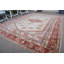Tapis turc en laine avec des motifs géométriques dans des tons de rouge chaud et de beige pour un décor de salon élégant