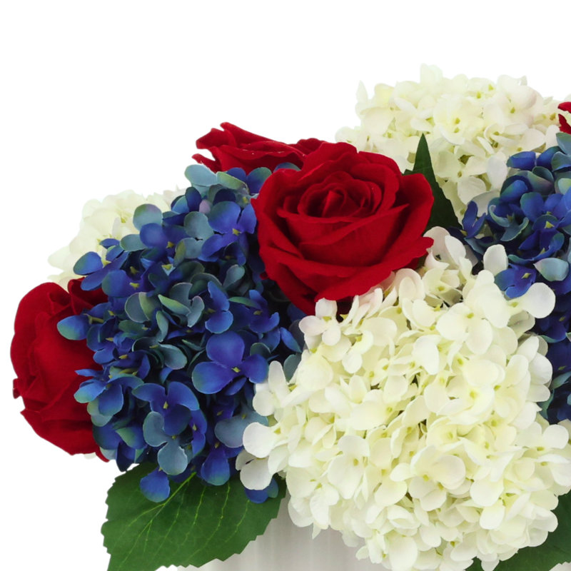 Arrangement d'hortensias et de roses rouges, blancs et bleus dans un vase plissé