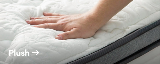 Mattress on wooden bedframe with pillows and blanket.