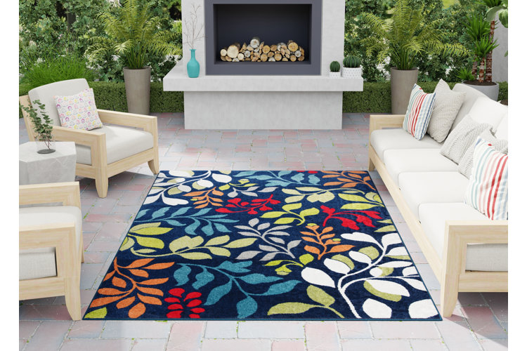 botanical leaf print hooked rug on a patio flanked by neutral furniture