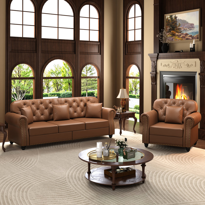 Canapé Chesterfield rembourré en similicuir avec capitonnage à boutons, garniture cloutée, accoudoirs roulés et coussins inclus pour un confort intemporel et une élégance moderne.