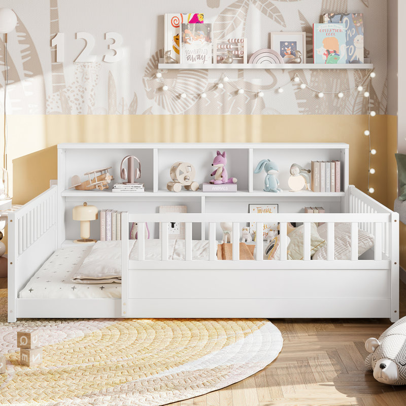 A full-sized wooden floor bed with a fence-style guardrail, featuring a side storage decorative function, and its color is white.