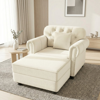 Fauteuil club velouté avec accoudoirs roulés, garniture cloutée et coussin décoratif