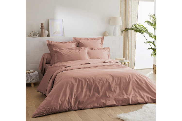 Pink percale sheets and pillowcases on a low-profile bed frame.