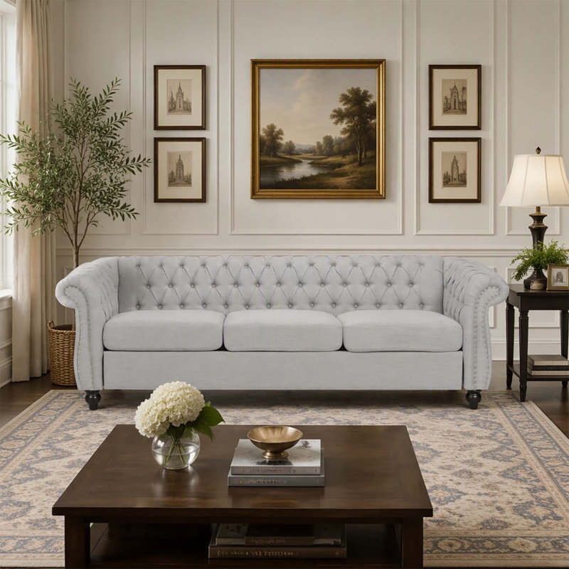 Canapé 3 places de style Chesterfield avec capitonnage à boutons, clous décoratifs et accoudoirs sculptés pour des espaces de vie élégants.