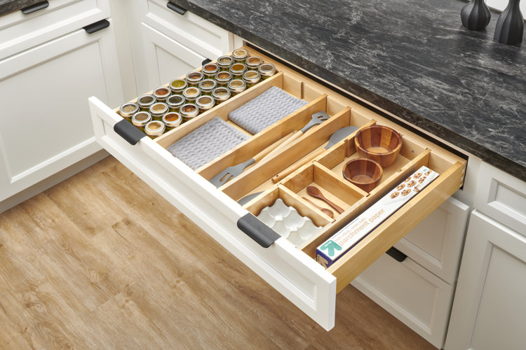kitchen drawer with parchment paper, dish towels, and spices organized with wooden dividers