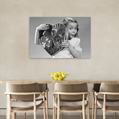 1950s Surpris petite fille regardant la caméra par derrière un grand cœur en forme de boîte de bonbons Saint-Valentin, rétro, rétro, art mural