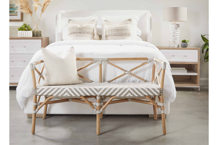 neutral bohemian bedroom with wicker-woven rattan bench in front of the bed