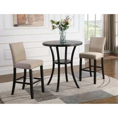 Table de bar ronde en bois, 3 chaises avec revêtement en tissu beige et pieds en métal, finition style salle à manger. Deux chaises assorties.