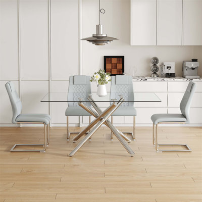 Ensemble de table de salle à manger moderne et luxueux en verre trempé transparent avec 4 chaises en polyuréthane gris clair et des pieds en métal argenté, parfait pour une salle à manger élégante et fonctionnelle