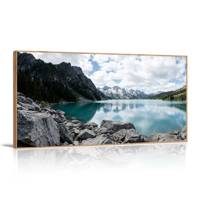 Tableau sur toile représentant un lac alpin turquoise avec des sommets enneigés et des rochers gris