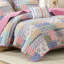 Couette rose à motifs floraux et à rayures audacieux, réversible pour une décoration polyvalente, en microfibre douce. Face avant patchwork ludique, revers uni apaisant. Confortable et facile à superposer.