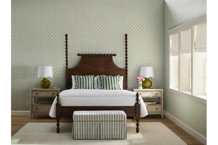 Vintage bedroom with polka-dot wallpaper, a four poster bed, striped pillows, and a skirted bench at the end of the bed.