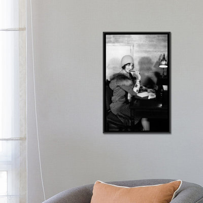 «Femme souriante des années 1920 avec un stylo à lèvres portant un chapeau de cloche et un manteau de col en fourrure écrivant une lettre au bureau du hall de l'hôtel avec lampe», reproduction de photo sur toile tendue