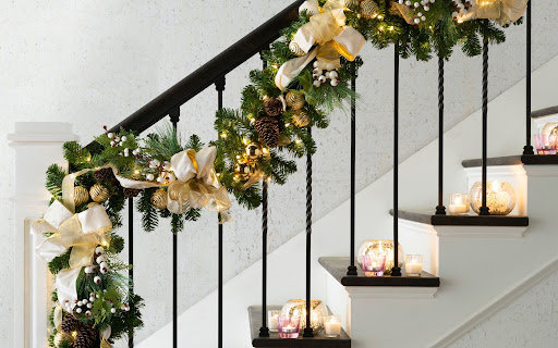 A banister decorated with a garland and string lights.
