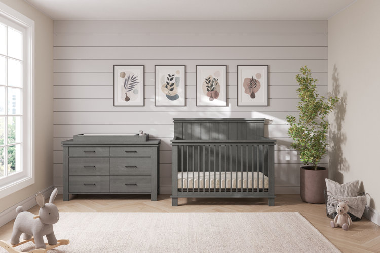 children's nursery with gray furniture, beige rug, gray shiplap walls, a plant, and pink botanical wall art
