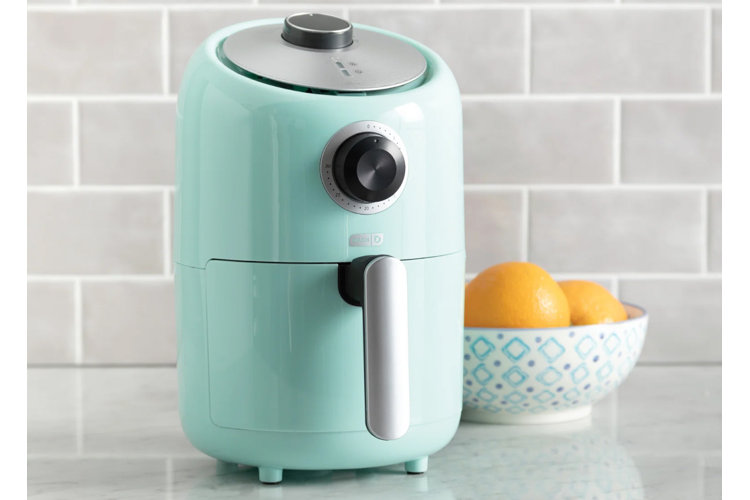teal small air fryer next to a bowl of oranges