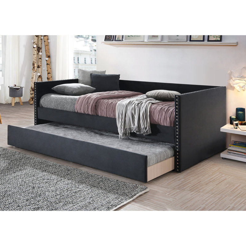 Lit de jour contemporain noir avec garniture cloutée et lit gigogne intégré, pour une chambre à coucher au style moderne et innovant.