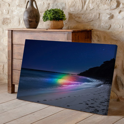 Canvas A Serene Beach Scene At Night Featuring Gentle Waves Lapping Wall Art At The Shore Illuminated By A Vibrant Rainbow Light Canvas Wall Art