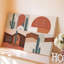 La toile crée un design abstrait visuellement saisissant mettant en vedette des cactus stylisés contre un art mural sur fond texturé-1553740357