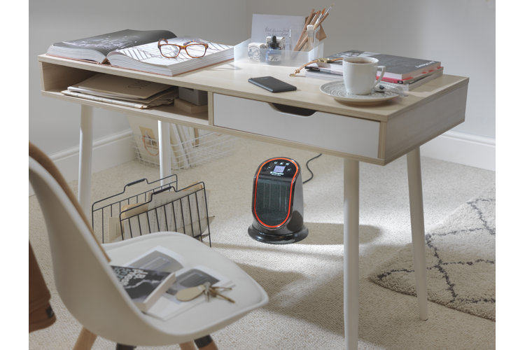 Black and red plug-in space heater on the floor beneath a white desk in a home office.
