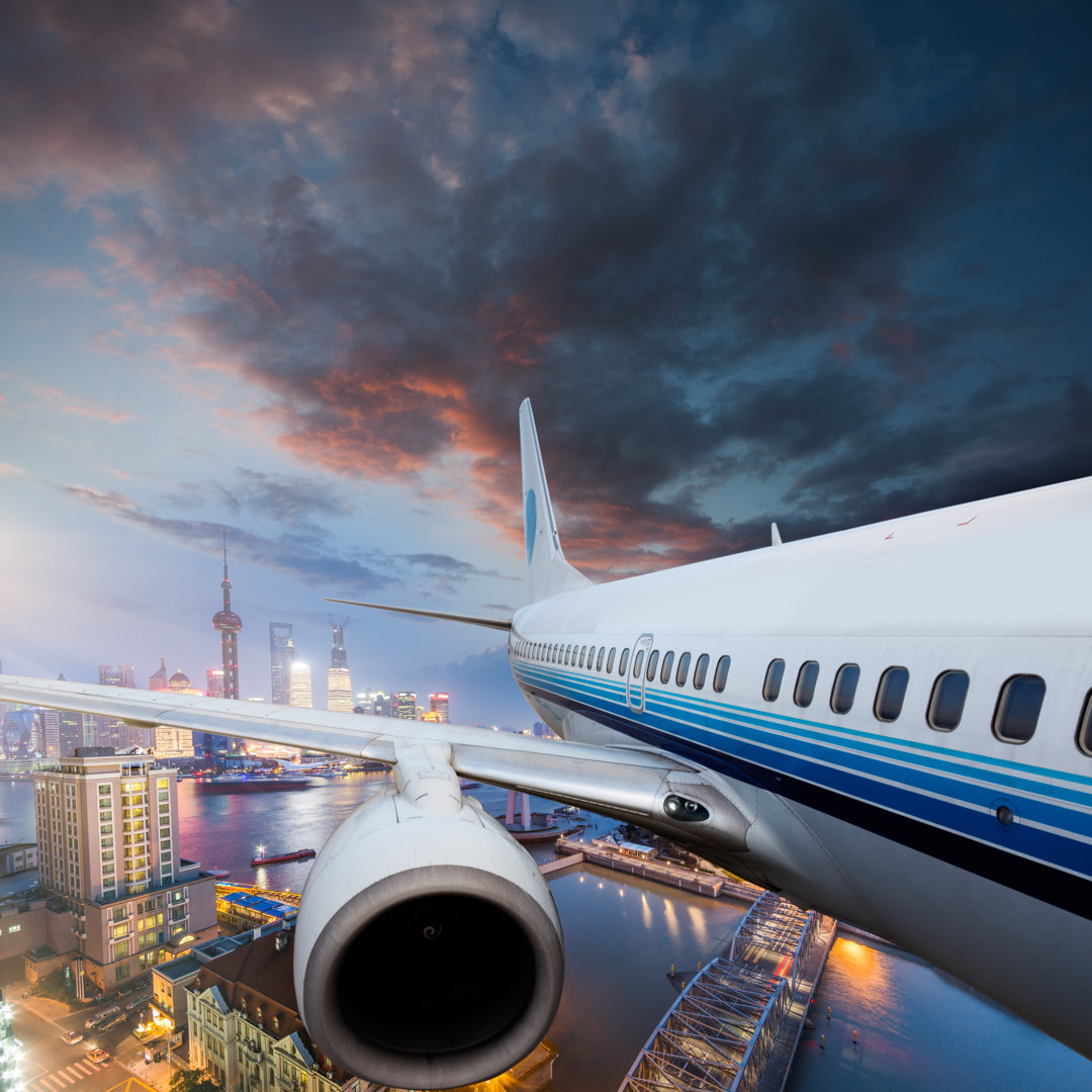 Flugzeug fliegt über die Stadt - Foto auf Leinwand