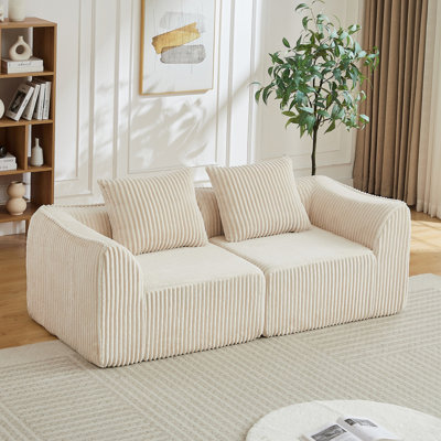 Canapé minimaliste en velours côtelé aux lignes courbes et au dossier légèrement incliné, livré avec deux coussins décoratifs, un coussin décoratif en forme de corne