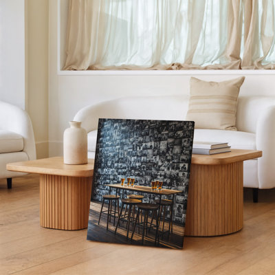 Canvas A Cozy Bar Scene Featuring A Wooden Table With Four Wall Art High Stools Set Against A Striking Black And White Collage For Canvas Wall Art