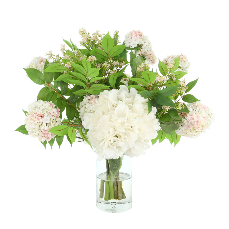 Hortensias et viburnum disposés dans un vase en verre