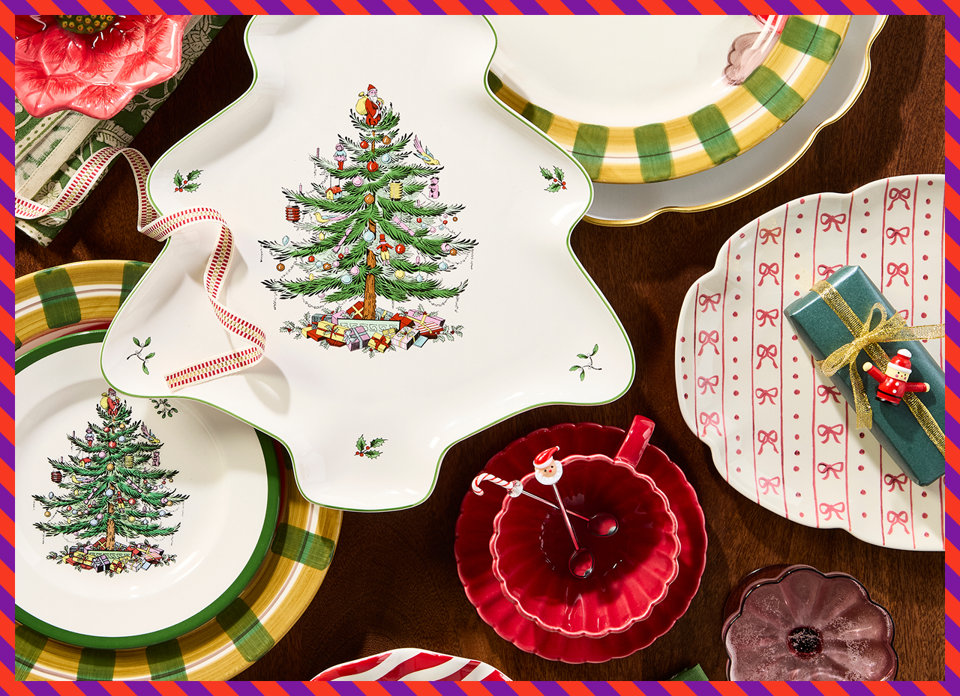 Top-down view of Christmas dinnerware featuring a tree-shaped platter, plates with festive tree and ribbon patterns, a red bowl with Santa spoons, and wrapped gifts on a wooden table.