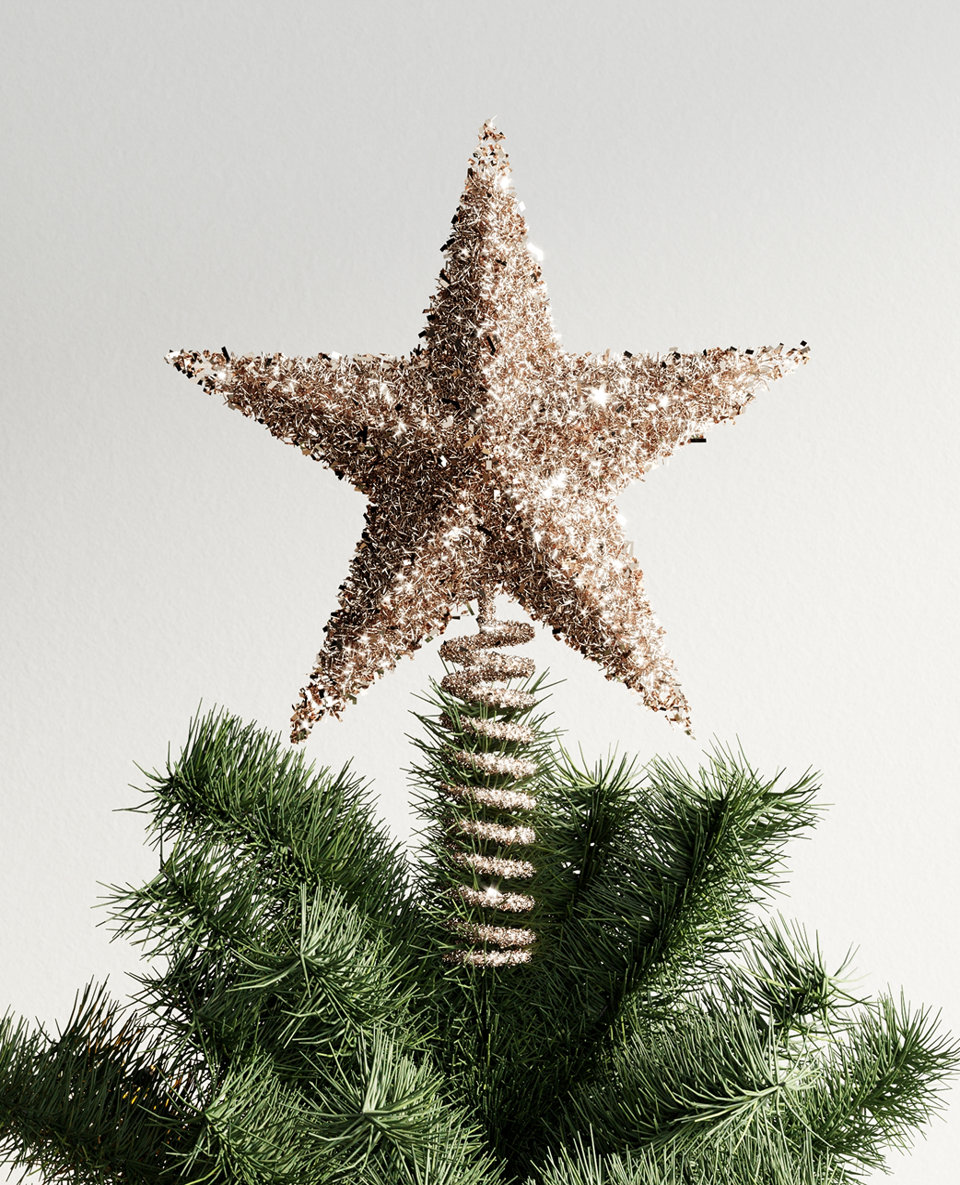 Close up of a Christmas tree topped with a gold star.
