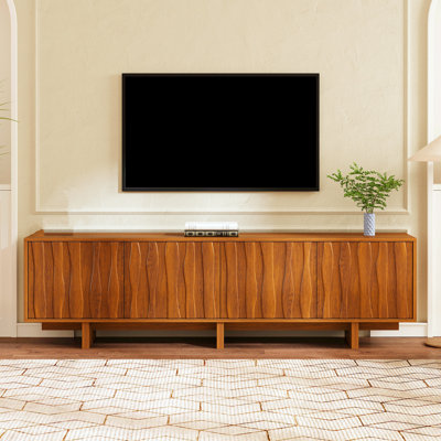 Console télé rétro à grain de bois avec portes d'armoire ondulées et système de gestion des câbles. Idéal pour les salons et les téléviseurs jusqu'à 75 pouces. Console média de style champêtre au fini noyer.