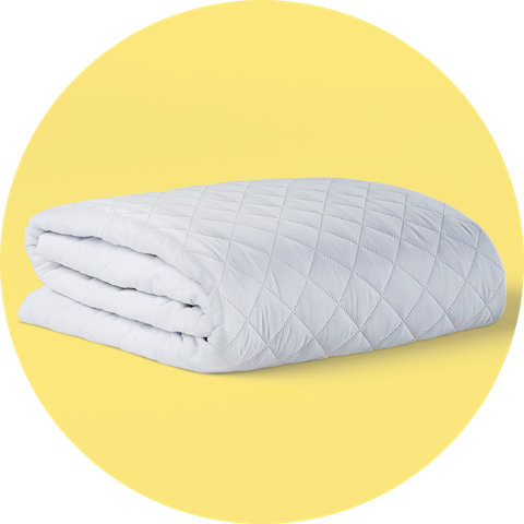 A thick, quilted white mattress pad or comforter neatly folded on a circular yellow background.