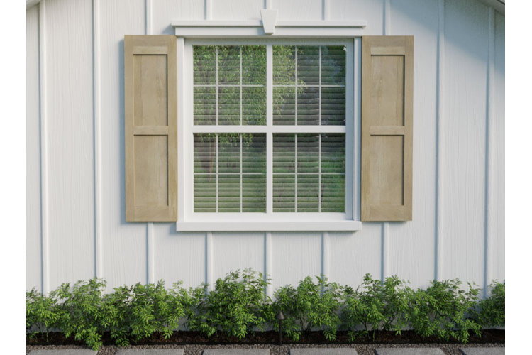 Home exterior with a large window, bookended on each side by wooden shutters and directly above a row of shrubs.