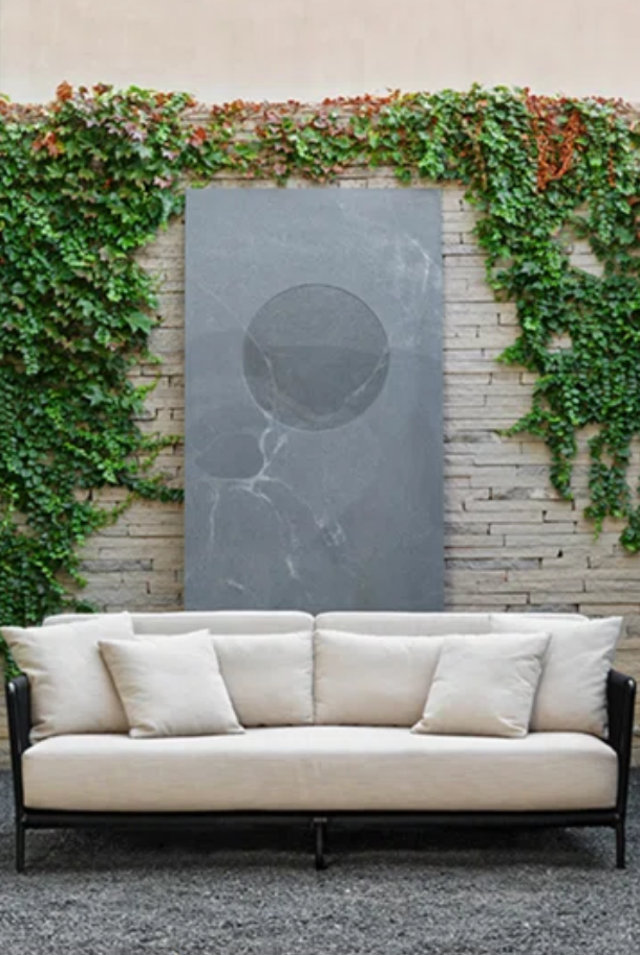 Neutral-colored sofa with a gray marble backdrop and ivy.